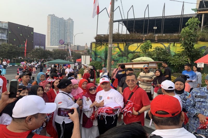 Wali Kota Depok, Supian Suri bersama Ketua TP-PKK Kota Depok, Siti Barkah Hasanah atau Cing Ikah saat membagikan bendera di kawasan HBKB Margonda, Minggu (09/08/26). (Sumber foto: Siaran Depok/AN Rafi)