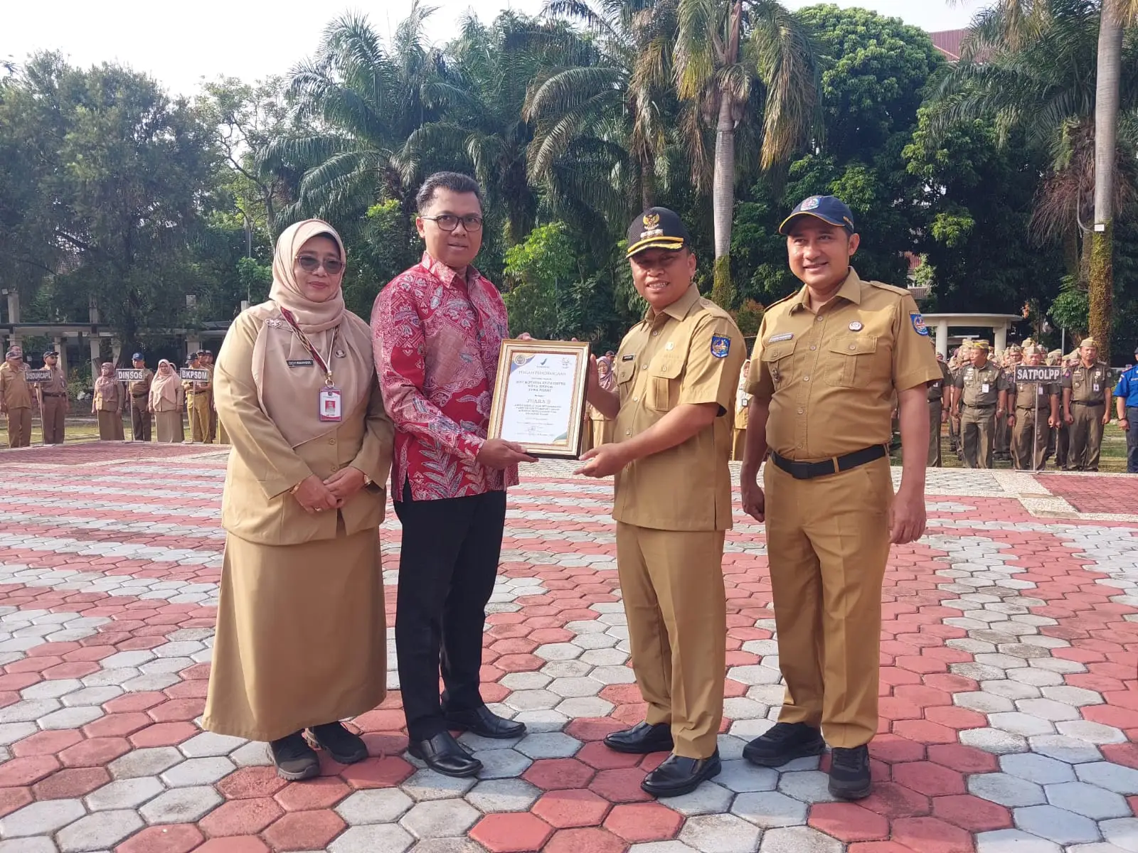 Wali Kota Depok, Supian Suri, bersama Wakil Wali Kota Depok, Chandra Rahmansyah dan Kepala Dinas Kesehatan Devi Maryori menyerahkan penghargaan Juara 3 Pembudayaan Keamanan Pangan dari BPOM saat pimpin Apel Pagi di Lapangan Balai Kota Depok pada Senin (26/10/2026). (Foto: Diskominfo Depok)